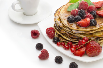 Delicious pancakes with berries and maple syrup on a white background
