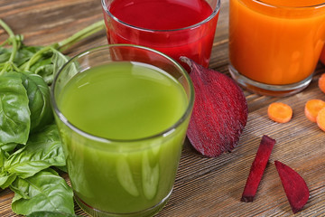 Glasses with various fresh juices and ingredients on table