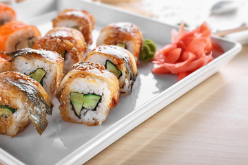 Plate with tasty sushi rolls on table, closeup