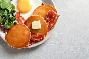 Tasty breakfast with pancakes, fried egg and bacon on table