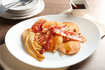 Tasty pancakes with bacon and banana on table