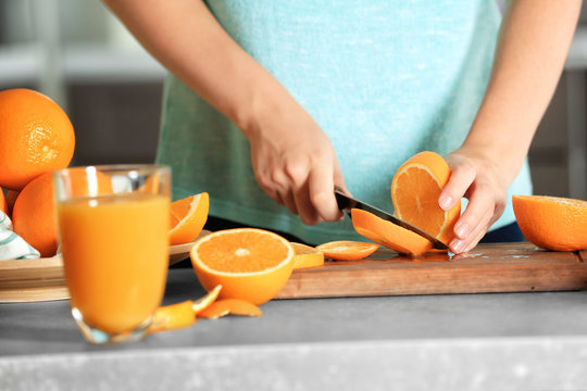 Woman cutting orange on board in kitchen