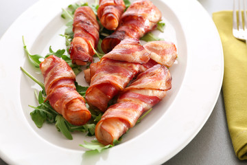 Plate with bacon wrapped chicken nuggets on table, closeup