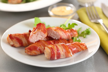 Plate with bacon wrapped chicken nuggets on table, closeup