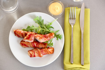 Plate with bacon wrapped chicken nuggets on table