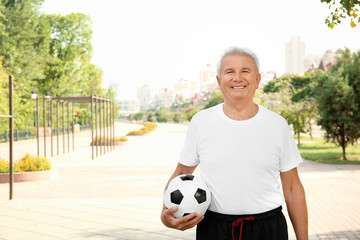 Mature man with soccer ball, outdoors