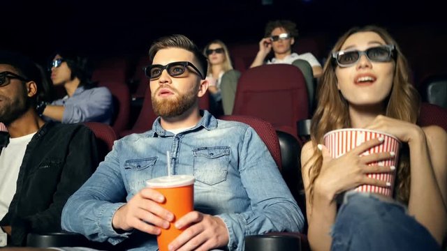 Young concentrated multiethnic audience watching film with popcorn in cinema
