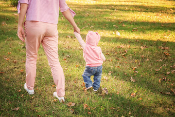 Mother with adorable little girl playing together in autumn park