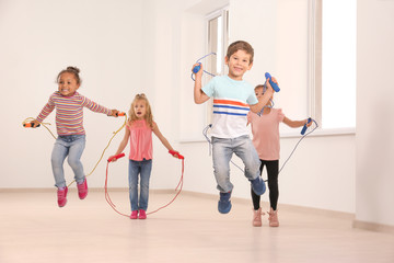 Cute children skipping rope in light room - obrazy, fototapety, plakaty
