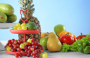 Composition with different fruits and vegetables on table against color background