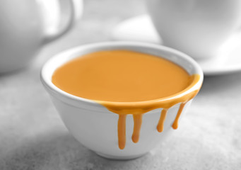 Bowl with sweet caramel sauce on table