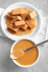 Plate with sweet caramel candies and sauce on table
