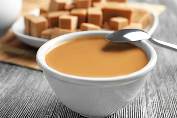 Bowl with sweet caramel sauce on table