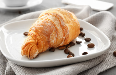 Plate with tasty croissant on table, closeup