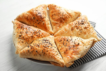 Delicious baked samosas with sesame seeds on light background