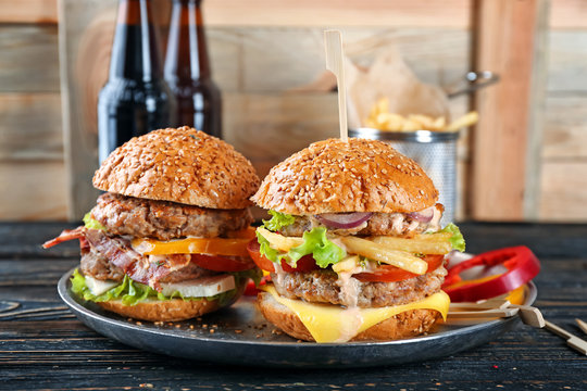 Dish with tasty double burgers on table