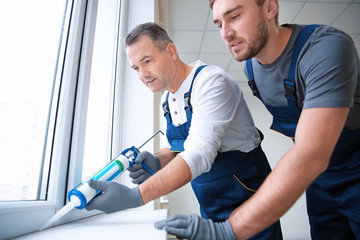 Construction worker with trainee installing window in house