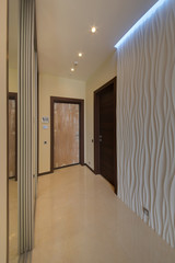 Corridor with dark doors and a relief white wall