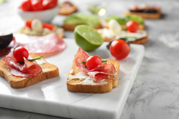 Delicious sandwiches with salami and cherry tomatoes on board, closeup