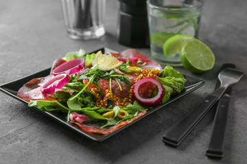 Plate with delicious fresh salad on table
