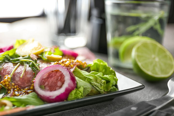 Plate with delicious fresh salad on table