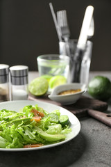 Plate with delicious fresh salad on table