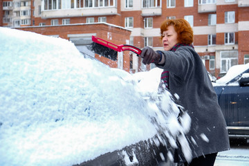 a woman cleans snow from the car