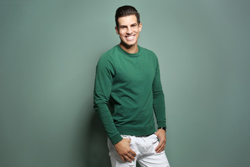 Handsome young man in casual clothes on color background
