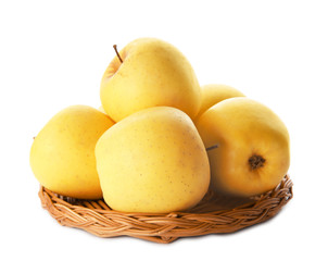 Wicker plate with ripe yellow apples on white background