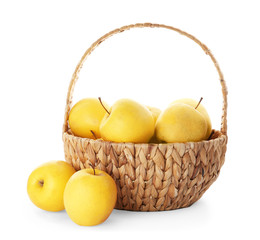 Wicker basket with ripe yellow apples on white background
