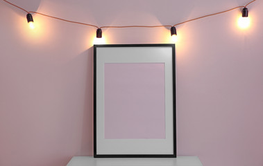 Mockup of blank frame with garland on light background