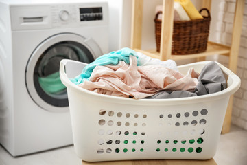 Fototapeta na wymiar Basket with laundry and washing machine in bathroom