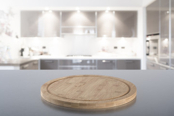 Empty cutting board on steel table with blurred modern kitchen background. Ready for product montage.