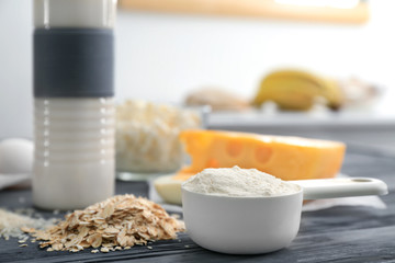 Fototapeta na wymiar Scoop with protein powder and products on table