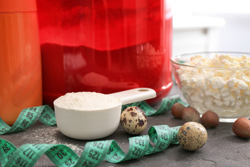 Scoop with protein powder, measuring tape and quail eggs on table