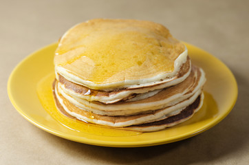 stack of pancakes on a yellow plate with honey
