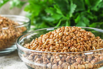 Raw buckwheat in glass bowls on sackcloth on a wooden background. Healthy diet food.