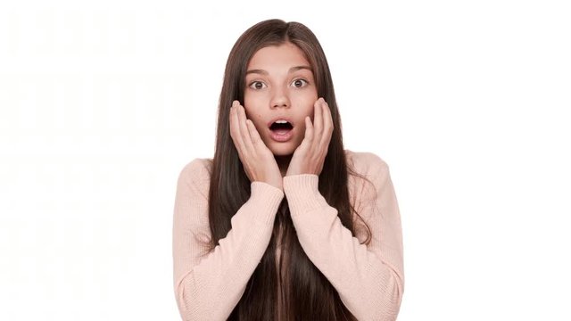 Closeup portrait of young scared woman 20s expressing fright with open mouth being shocked hearing bad news raising hands to cheeks in fear over white background. Concept of emotions