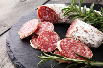Stone cutting board with sliced salami on it