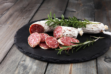 Stone cutting board with sliced salami on it