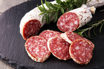 Stone cutting board with sliced salami on it