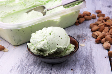 scoop of pistachio ice cream with pistachios on wooden background