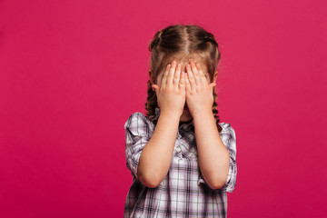 Little girl child standing isolated covering face with hands.