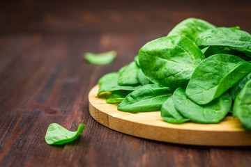 Fresh juicy spinach leaves on a wooden brown table. Natural products, greens, healthy food, vitamins.