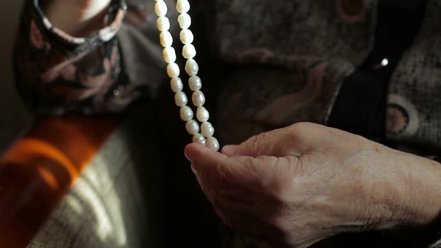 Beads from pearls in the hands of an old lady, close-up