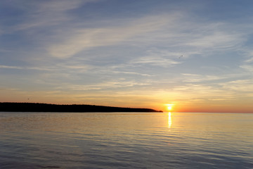 Obraz premium A view of the calm golden sunset on the river with the sun reflected in it, Volga, Russia