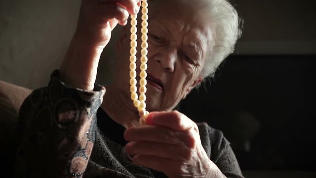 Beads from pearls in the hands of an old lady, close-up