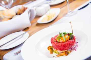 Steak tartare served in a restaurant with egg yolk,  onions, caper, mushroom and rocket salad