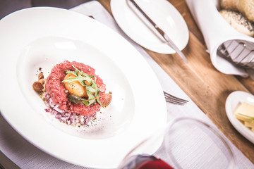 Steak tartare served in a restaurant with egg yolk,  onions, caper, mushroom and rocket salad