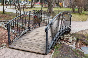 Bridge of wood and cast iron through a stream with padlocks-symbols of love
